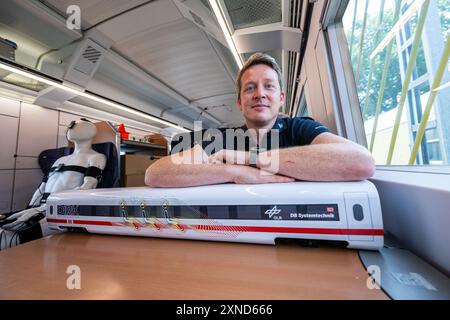 Minden, Deutschland. 31. Juli 2024. Daniel Schmeling, Deutsches Zentrum für Luft- und Raumfahrt (DLR), sitzt zusammen mit einem Modell der Deutschen Bahn in einem Versuchswagen, in dem DLR und Deutsche Bahn Aerodynamik und Strömungstechnik testen. Das Deutsche Zentrum für Luft- und Raumfahrt (DLR) Göttingen erforscht Klimaanlagen für Züge in einem Versuchswagen der Deutschen Bahn. Quelle: Guido Kirchner/dpa/Alamy Live News Stockfoto