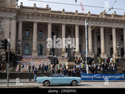 Melbourne, Australien. 31. Juli 2024. Ein Ford Mustang aus den 1960er Jahren fährt während der Veranstaltung an der Anzeige vorbei. 6.000 Origami-Häuser wurden vom Victorian Homeless Network auf den Stufen des Parlamentsgebäudes von Victoria platziert und symbolisieren 10 % der Sozialwohnungen, die im Staat benötigt werden, um die Obdachlosigkeit zu beenden. Quelle: SOPA Images Limited/Alamy Live News Stockfoto