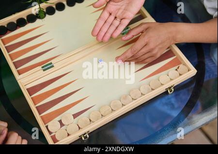 Blick von oben auf zwei Personen, die Backgammon auf einem Holzbrettspiel spielen. Sie nehmen an einem strategischen Spiel Teil, genießen Outdoor-Freizeit und schöne Zeit. Stockfoto