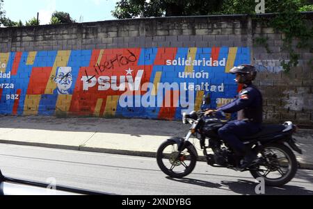 Valencia, Carabobo, Venezuela. 31. Juli 2024. 31. Juli 2024. Ein Motorradfahrer fährt vor Graffiti, die während der Proteste gegen die Ergebnisse der Präsidentschaftswahlen in Valencia, Bundesstaat Carabobo, gekratzt wurden. Foto: Juan Carlos HernÃndez (Foto: © Juan Carlos Hernandez/ZUMA Press Wire) NUR REDAKTIONELLE VERWENDUNG! Nicht für kommerzielle ZWECKE! Stockfoto