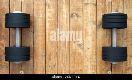 Schwarze und graue Kurzhanteln auf Holzboden im Heimtrainer für Krafttraining Stockfoto