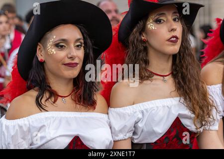 Dieses Bild zeigt Frauen in auffälligen schwarzen Hüten mit roten Federn sowie eleganten weißen, schwarzen und roten Kleidern Stockfoto