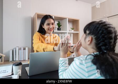 Mutter und Kind arbeiten von zu Hause aus, machen Spaß bei Aktivitäten, modernes Home Office-Setting Stockfoto