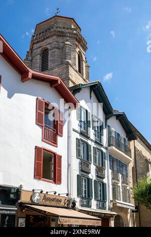 Frankreich, Region Nouvelle-Aquitaine, Saint-Jean-de-Luz, traditionelle Geschäfte und Gelato in der Rue Léon Gambetta mit der Kirche St. Johannes des Täufers dahinter Stockfoto