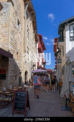 Frankreich, Region Nouvelle-Aquitaine, Saint-Jean-de-Luz, antike Steinhäuser in der Rue de la Republique mit Restaurant im Freien Stockfoto