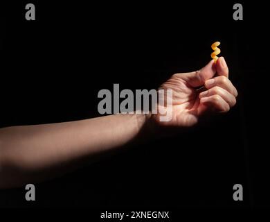 Pasta Cavatappi in der Hand auf schwarzem Hintergrund Stockfoto