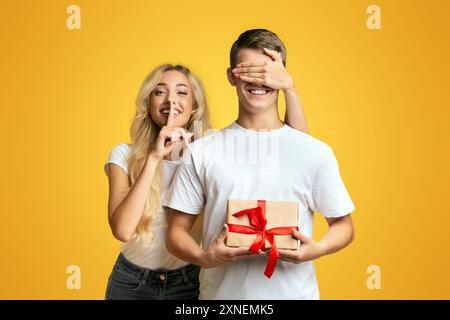 Lassen Sie sich überraschen. Mädchen die Augen ihres Freundes und stille Zeichen Stockfoto