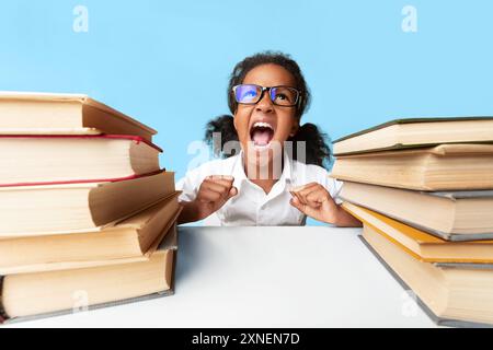 Böse Mädchen schreien Hausaufgaben saß zwischen Book Stacks Stockfoto