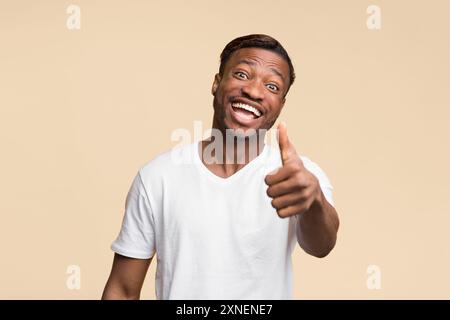 Positive Schwarzer Mann deutete Daumen hoch stehend Über gelben Hintergrund Stockfoto
