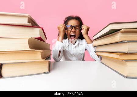 Kleines Schulmädchen schreien laut Sitzen zwischen Buch Stapel auf Gelb Stockfoto