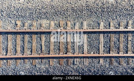 Aus der Vogelperspektive eines einzigen Eisenbahngleises mit Holzschwellen, die über einem Kiesbett laufen Stockfoto