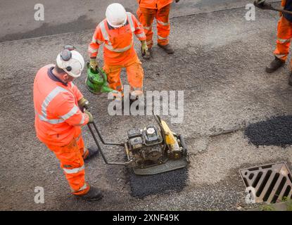 BUCKINGHAMSHIRE, Großbritannien - 19. März 2024. Straßenarbeiter reparieren Schlaglöcher. Provisorische Schlagloch-Patch-Reparaturen auf einer Landstraße im Verfall. Stockfoto