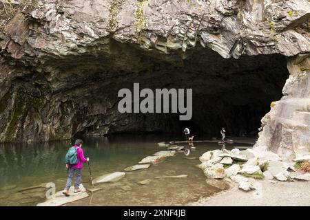 CUMBRIA, Großbritannien - 21. April 2024. Wanderer laufen auf Steinen am Eingang zur Rydal Cave in der Nähe von Ambleside, Lake District, Großbritannien Stockfoto