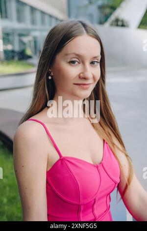 Porträt einer Frau in einem rosa Kleid in der Nähe eines Einkaufszentrums. Stockfoto