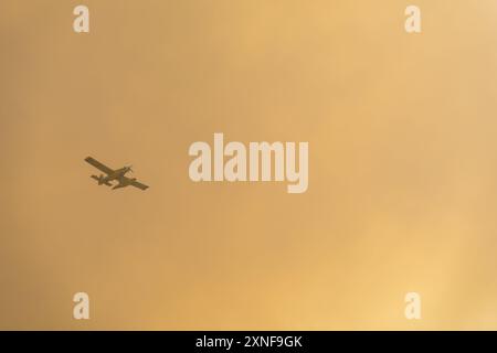 Löschflugzeug, das durch einen Waldbrand in eine große Rauchwolke fliegt Stockfoto