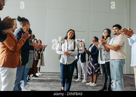 Verschiedene Mitarbeitergruppen klatschen und lächeln auf einer Geschäftskonferenz und betonen einen Moment des Feierns und der Leistung mit einem Fokus auf Frauen Stockfoto