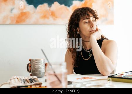Eine Künstlerin macht eine Pause, während sie einen Becher hält Stockfoto