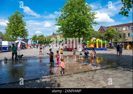 Valkenswaard, Nord-Brabant, Niederlande, 10. Juli 2024 - Kinder spielen am Brunnen auf dem Marktplatz Stockfoto