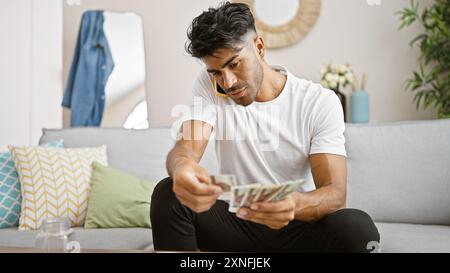Hübscher junger Mann, der polnische Zloty-Scheine in einem modernen Wohnzimmer zählt. Stockfoto