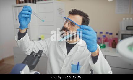 Reifer Mannwissenschaftler untersucht chemische Proben in einem Labor mit Handschuhen und Schutzbrille Stockfoto