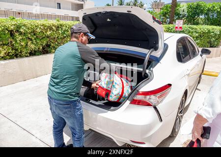 Miami Beach Florida, Hispanic Mann, arbeitender Fahrer, Verladen von Gepäck in Auto-Kofferraum Besucher besuchen Reise Reise Reise Reise Reise Tourismus, La Stockfoto