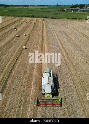 Garlieston, Wigtownshire, Schottland, Großbritannien - Mittwoch, 31. Juli 2024 – Luftaufnahme von Landwirten, die Maisstängel für die Strohernte an einem sonnigen, warmen Tag in den Feldern der ländlichen Dumfries & Galloway schneiden und pressen – die lokalen Temperaturen erreichten 22c mit Regenvorhersage für Freitag – Foto Steven May / Alamy Live Neuigkeiten Stockfoto