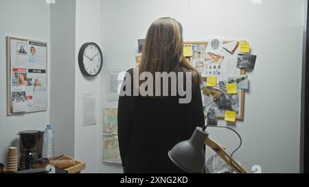 Eine Detektivin analysiert eine Kriminaluntersuchungsstelle in einem Büro, umgeben von Beweisen und Hinweisen. Stockfoto