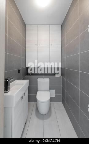 Winziges WC WC WC Heim Innenraum. Sinket und Wasserhahn im Vordergrund, Kabinett im Hintergrund. Fliesenwände Stockfoto