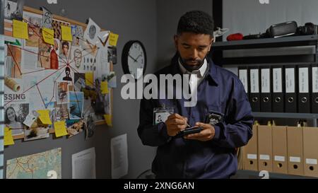 Ein fokussierter junger afroamerikaner mit Bart, der sich Notizen im Büro eines Detektivs macht, umgeben von Ermittlungshinweisen und Akten. Stockfoto