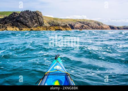 Ein Seekajak in den Gezeitenrennen von Rhoscolyn Beacon vor Anglesey, Nordwales Stockfoto