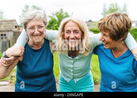 Drei ältere Frauen teilen sich einen intimen Moment des Lachens und der Verbindung in einem Garten. Aufrichtige Freundschaft, emotionale Bindung und die Freude daran einfangen Stockfoto