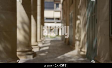 Verschwommener Innenhof mit sonnendurchfluteten Säulen, Schatten und defokussierten architektonischen Details Stockfoto