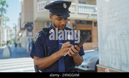 afroamerikanischer Polizist macht Notizen auf Tablets auf der Straße der Stadt. Stockfoto