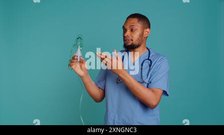 Männliche Krankenschwester, die ein medizinisches Unterrichtsvideo über die Verwendung von Handnebulizer für die Abgabe von Medikamenten auf Aerosolbasis macht. Medic präsentiert Inhalationsgerät für Lungenerkrankungen wie Lungenentzündung, Kamera B Stockfoto