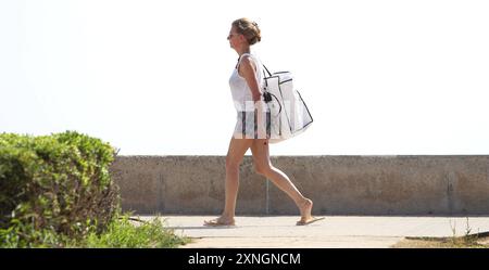 Eine junge Frau geht an der Promenade am Strand von Playa de Palma entlang. Mallorca Spanien *** Eine junge Frau spaziert entlang der Strandpromenade in Playa de Palma Mallorca Spanien Stockfoto