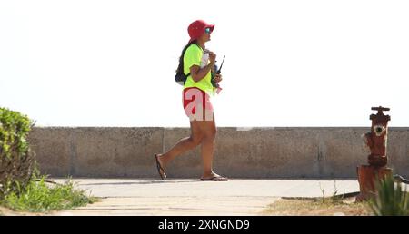 Eine junge Frau geht an der Promenade am Strand von Playa de Palma entlang. Mallorca Spanien *** Eine junge Frau spaziert entlang der Strandpromenade in Playa de Palma Mallorca Spanien Stockfoto