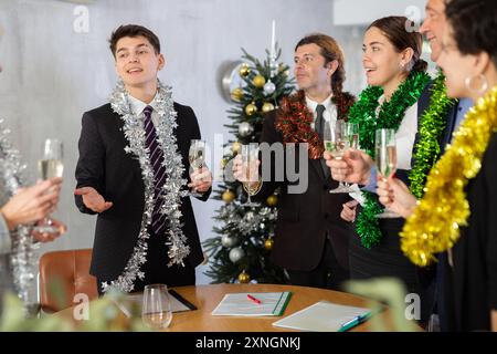 Fröhlicher Kerl, der Toast während der Neujahrsfeier mit Kollegen anbietet Stockfoto