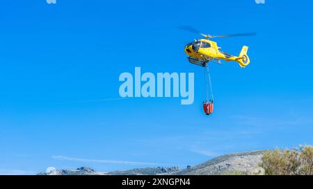 Hubschrauber auf Flussbett mit Korb voller Wasser Stockfoto