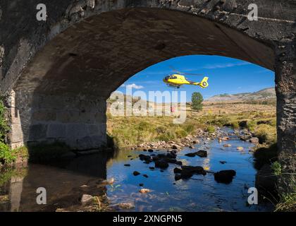 Hubschrauber auf Flussbett mit Korb voller Wasser Stockfoto