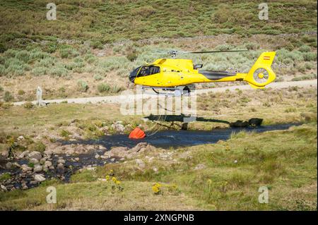 Hubschrauber auf Flussbett mit Korb voller Wasser Stockfoto