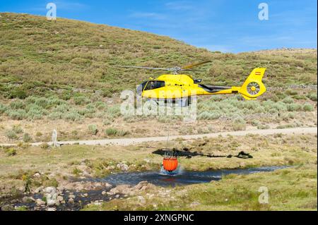 Hubschrauber auf Flussbett mit Korb voller Wasser Stockfoto