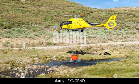 Hubschrauber auf Flussbett mit Korb voller Wasser Stockfoto