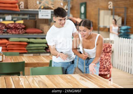 Ein junges verheiratetes Paar wählt einen Holztisch für seinen Garten im Gartenladen Stockfoto