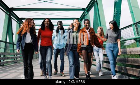 Junge multirassische Gruppe von Freunden, die Spaß in Reiseurlauben haben. Multikulturelle Menschen, die auf der Stadtbrücke spazieren Stockfoto