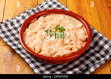 Hausgemachtes Hühnerstroganoff in Keramikschale auf rustikalem Holztisch. Draufsicht Stockfoto