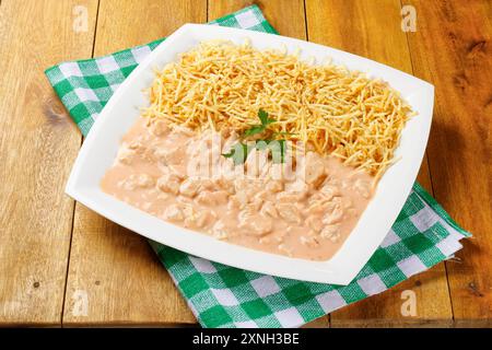 Hausgemachter Hähnchenstroganoff in Keramikplatte auf roter karierter Tischdecke. Draufsicht Stockfoto