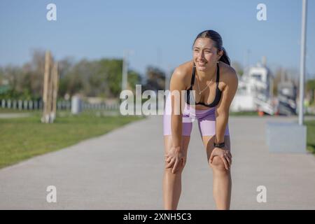 Müde Latina-Läuferin, die sich ausgeruht hat, nachdem sie in einem öffentlichen Park mit Kopierraum gelaufen ist. Stockfoto