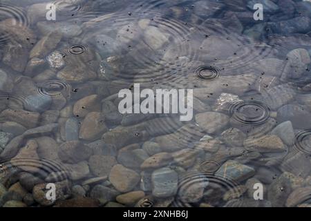 Hintergrundbild von klarem Wasser mit Felsen unter der Oberfläche im Sommer. Tapete, beruhigend, makelloses Foto. Regentropfen, Regen auf der Oberfläche. Stockfoto