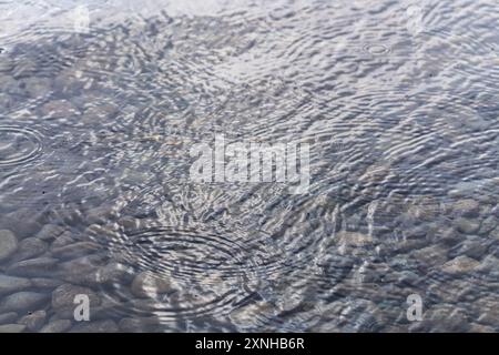 Hintergrundbild von klarem Wasser mit Felsen unter der Oberfläche im Sommer. Tapete, beruhigend, makelloses Foto. Regentropfen, Regen auf der Oberfläche. Stockfoto