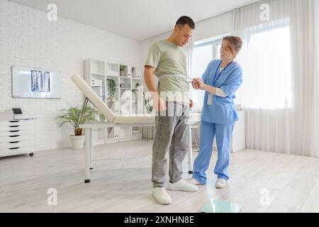 Ärztin, die die Taille des Mannes in der Klinik misst Stockfoto